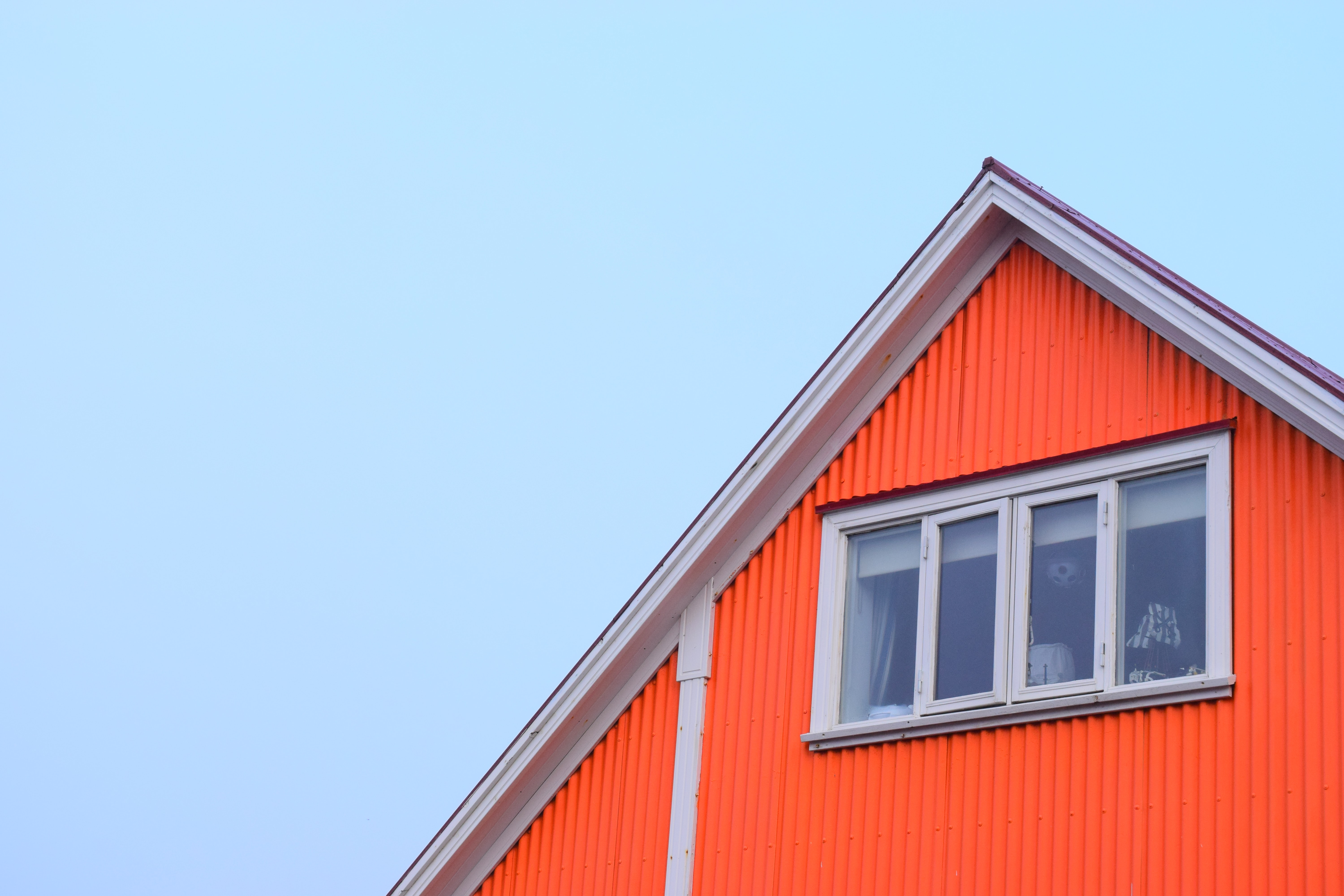 Photo of orange house peak in Iceland with window in center, can see lamp through window
